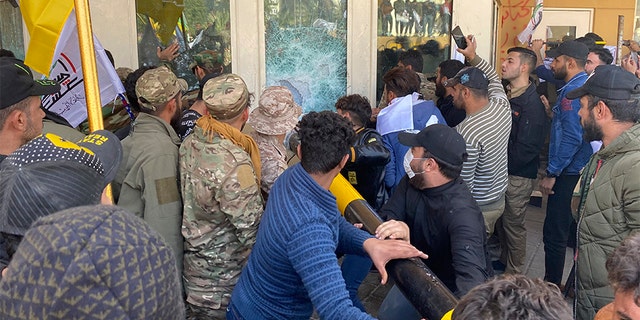 Protesters smash a window inside the U.S. embassy compound in Baghdad on Tuesday. (AP)