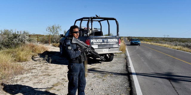 Police guard the highway leading to ViIlla Union, Mexico, Sunday, Dec. 1, 2019, the day after it was assaulted by gunmen.