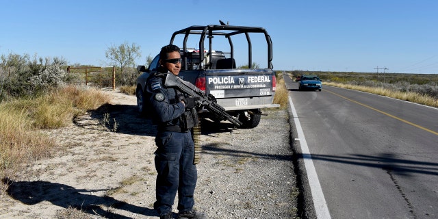 Police guard the highway leading to ViIlla Union, Mexico, Sunday, Dec. 1, 2019, the day after it was assaulted by gunmen.