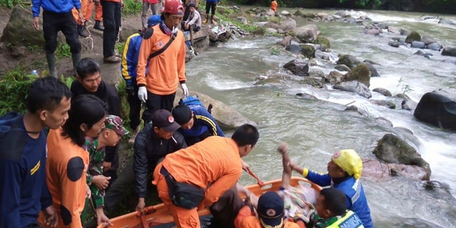In this photo released by the National Search And Rescue Agency (BASARNAS), rescuers remove the body of a victim of a bus accident in Pagaralam, Indonesia, Tuesday, Dec. 24, 2019. A number of people were killed when the passenger bus plunged into the ravine on Sumatra island after its brakes apparently malfunctioned, police said Tuesday. (BASARNAS via AP)