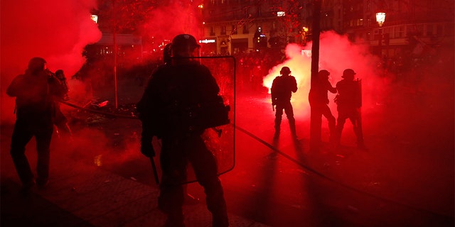 Riot police officers secure an area as some demonstrators were seen smashing store windows, setting fires and hurling flares in eastern Paris Thursday. (AP)