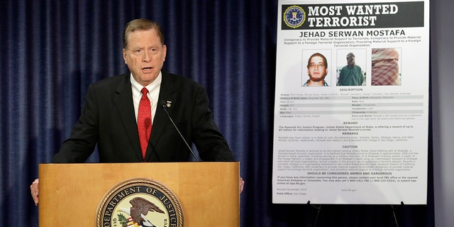 U.S Attorney Robert Brewer speaks in front of an FBI poster depicting Jehad Serwan Mostafa during a news conference Monday, Dec. 2, 2019, in San Diego. The U.S. attorney's office in San Diego says the 37-year-old U.S. citizen who is on the FBI's Most Wanted Terrorist List is facing a new indictment. (AP Photo/Gregory Bull)