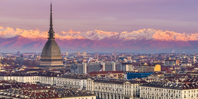 Torino (Turin, Italy): cityscape at sunrise with details of the Mole Antonelliana towering over the city. Scenic colorful light on the snowcapped Alps in the background.