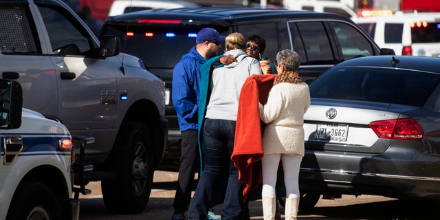 Residents embrace near police and fire cars that surround the scene of a shooting at West Freeway Church of Christ in White Settlement, Texas, Sunday, Dec. 29, 2019.