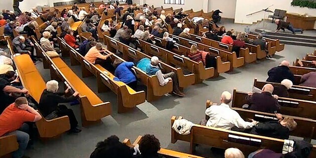 In this still frame from livestreamed video provided by law enforcement, churchgoers take cover while a congregant armed with a handgun, top left, engages a man who opened fire, near top center just right of windows, during a service at West Freeway Church of Christ, Sunday, Dec. 29, 2019, in White Settlement, Texas.