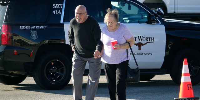 An elderly couple walks from West Freeway Church of Christ hours after a fatal shooting at the church, Sunday, Dec. 29, 2019, in White Settlement, Texas.