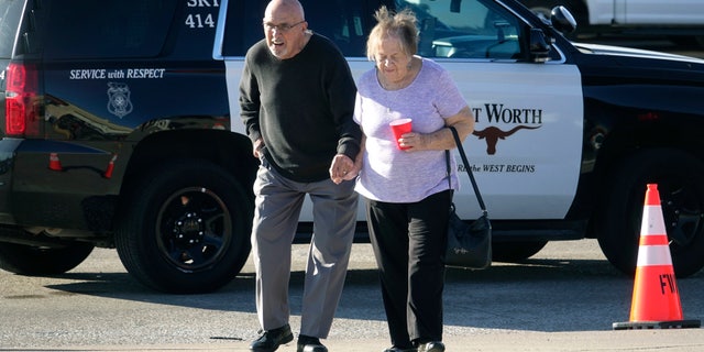 An elderly couple walks from West Freeway Church of Christ hours after a fatal shooting at the church, Sunday, Dec. 29, 2019, in White Settlement, Texas.