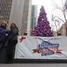 People pose for a picture in front of the Christmas tree in FOX Square in New York City.