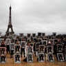 A hundred activists hold portraits of President Emmanuel Macron upside down to urge France to take action during the U.N. COP 25 climate during a gathering at Place du Trocadero in Paris, Dec. 8, 2019. 