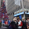 People stop to have their picture taken in front of the Christmas tree in FOX Square in New York City.
