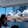 Tourists on a boat photograph the eruption of the volcano on White Island, New Zealand, Dec. 9, 2019. 