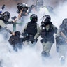 Police in riot gear move through a cloud of smoke as they detain a protester at the Hong Kong Polytechnic University in Hong Kong, Nov. 18, 2019. 