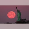 The Super Snow Moon sets behind the Statue of Liberty as the sun rises in New York City, February 19, 2019. 
