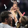 Quarterback Tom Brady of the New England Patriots and his daughter Vivian celebrate with the Vince Lombardi trophy after New England won Super Bowl LIII in Atlanta, Feb. 03, 2019.