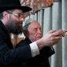 Moscow, Russia: Holocaust survivor WWII veteran Mikhail Spectr, 86, center, helped by Rabbi Aaron Mamut, lights of a menorah during the annual Hanukkah Menorah Lighting Ceremony. 