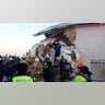 In this photo provided by the Emergency Situations Ministry of the Republic of Kazakhstan, police and rescuers work on the side of a plane crashed near Almaty International Airport.