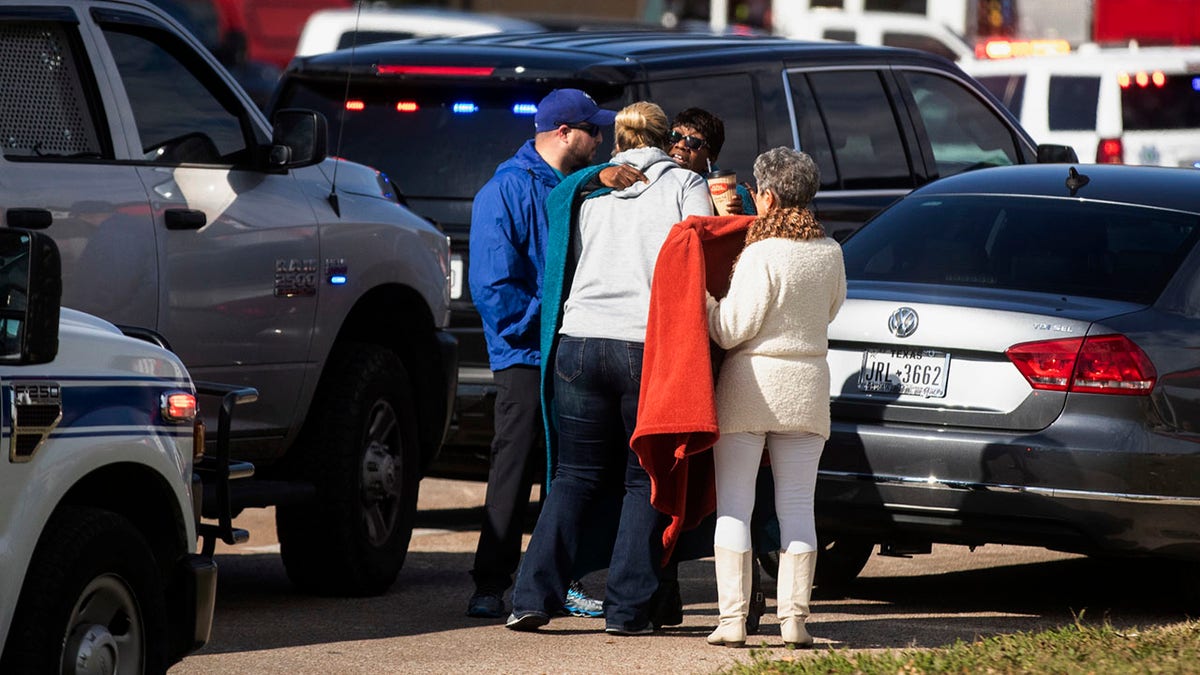 Residents embrace near police and fire cars that surround the scene of a shooting at West Freeway Church of Christ in White Settlement, Texas, Sunday, Dec. 29, 2019. (Yffy Yossifor/Star-Telegram via AP)