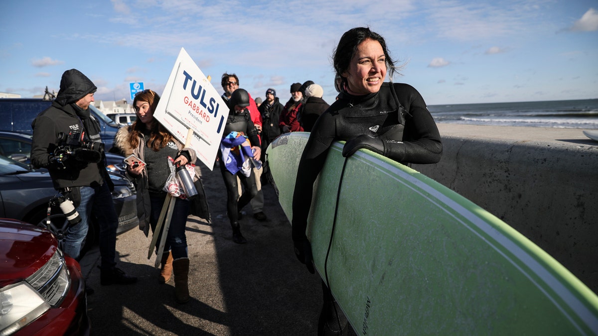Democratic presidential candidate U.S. Rep. Tulsi Gabbard, D-Hawaii, carries her surfboard after surfing the Atlantic Ocean, Wednesday, Jan. 1, 2020, in Hampton, N.H. (AP Photo/Cheryl Senter)