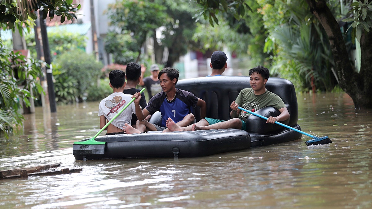 Residents use an inflatable chair as a raft to make their way through a flooded neighborhood in Tanggerang on the outskirts of Jakarta, Indonesia, Thursday, Jan. 2, 2020. Heavy flooding in Indonesia's capital as residents celebrated the new year has killed over a dozen, displaced tens of thousands and forced an airport to close, the country's disaster management agency said Thursday. (AP Photo/Tatan Syuflana)