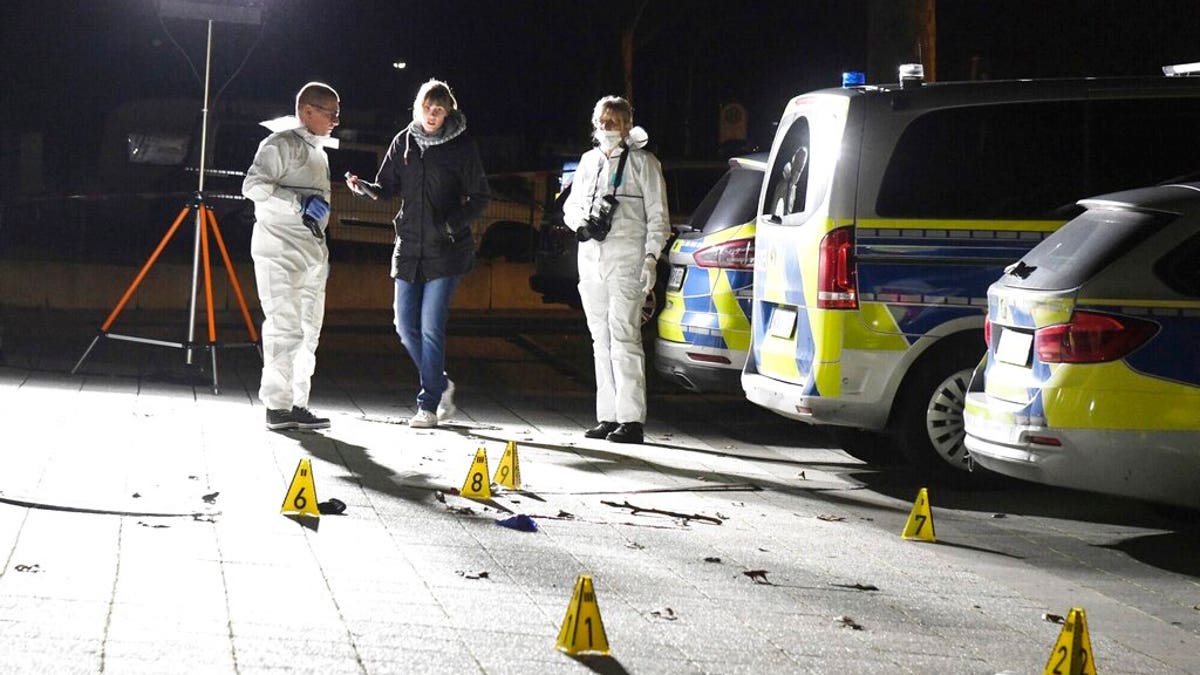 Police officers investigate inside a cordoned-off area in front of a police station in Gelsenkirchen, Germany, late Sunday, Jan. 5, 20120. (Stephan Witte/dpa via AP)