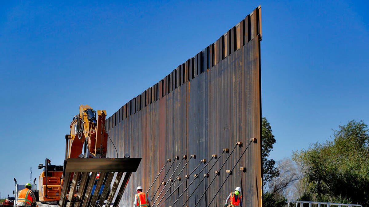 FILE: Government contractors erect a section of Pentagon-funded border wall along the Colorado River in Yuma, Ariz.