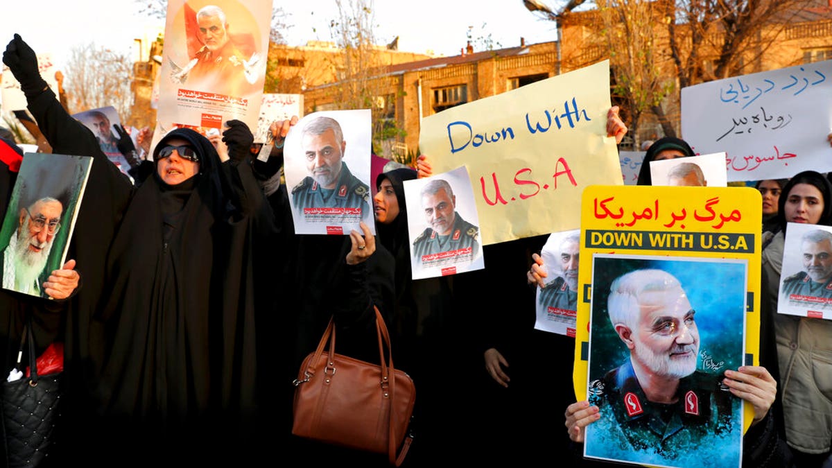 Protesters chant slogans and hold up posters of Gen. Qassem Soleimani during a demonstration in front of the British Embassy in Tehran, Iran, Sunday, Jan. 12, 2020. A candlelight ceremony late Saturday in Tehran turned into a protest, with hundreds of people chanting against the country's leaders — including Supreme Leader Ayatollah Ali Khamenei — and police dispersing them with tear gas. Police briefly detained the British ambassador to Iran, Rob Macaire, who said he went to the Saturday vigil without knowing it would turn into a protest. (AP Photo/Ebrahim Noroozi)