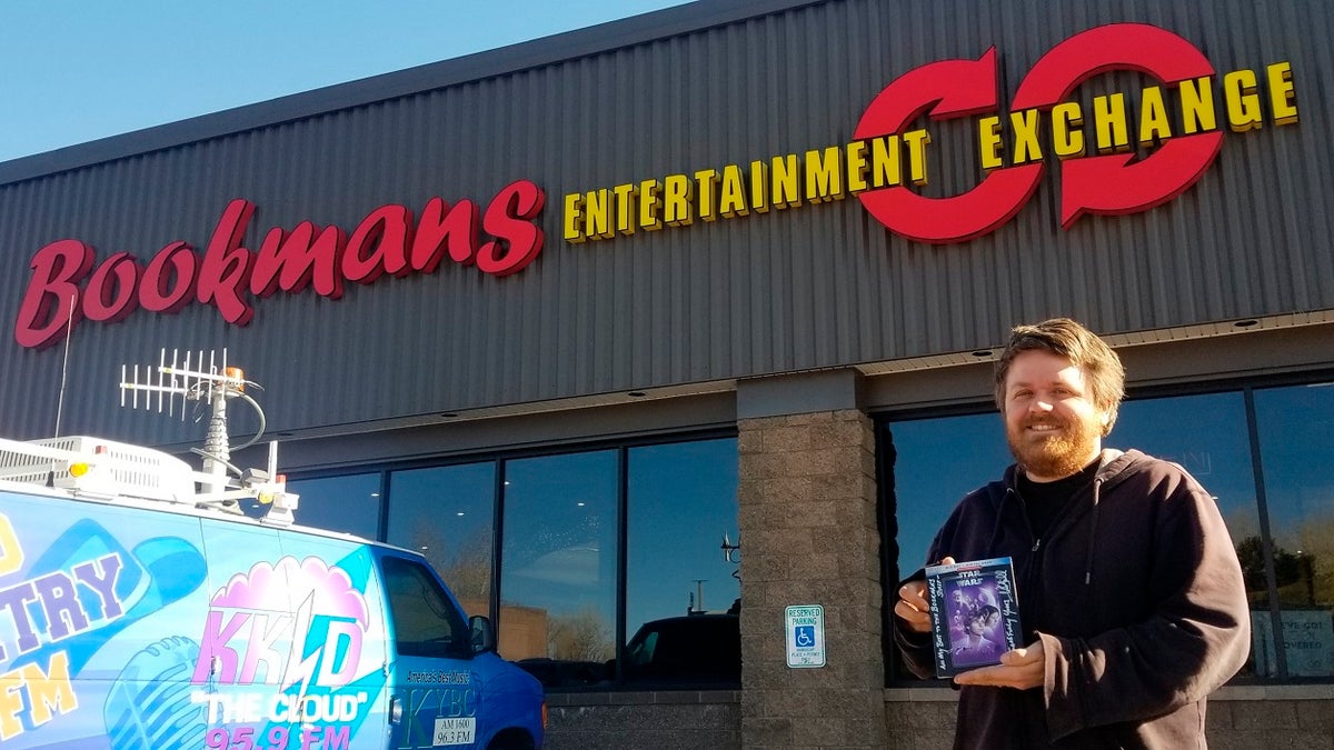 Bookmans Entertainment Exchange general manager Micheil Salmons stands in front of the store in Flagstaff, Ariz., holding a DVD autographed by Star Wars actor Mark Hamill. (Scott Buffon/Arizona Daily Sun via AP)