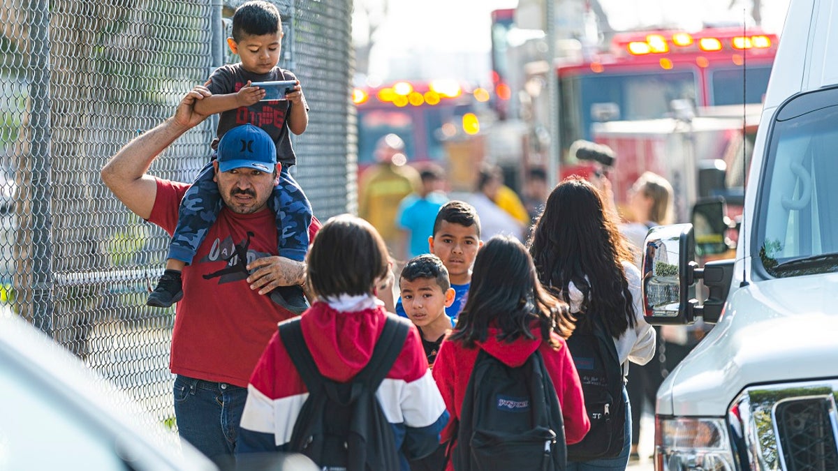 Children evacuate the Park Avenue Elementary school in Cudahy, Calif., on Tuesday. Fire officials say fuel apparently dumped by the aircraft returning to LAX fell onto the school's playground. (AP Photo/Damian Dovarganes)