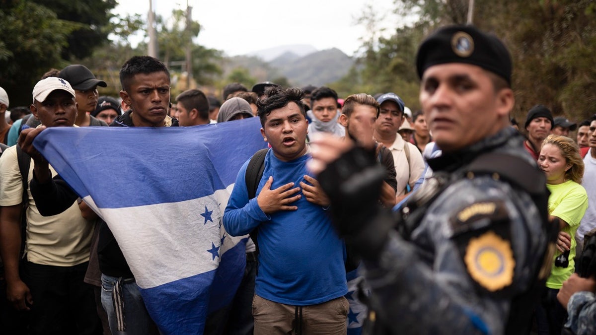 Honduran migrants walking in a group stop before Guatemalan police near Agua Caliente, Guatemala on Thursday on the border with Honduras. Hundreds of Honduran migrants started walking and hitching rides Wednesday from the city of San Pedro Sula, in a bid to form the kind of migrant caravan that reached the U.S. border in 2018. (AP Photo/Santiago Billy)