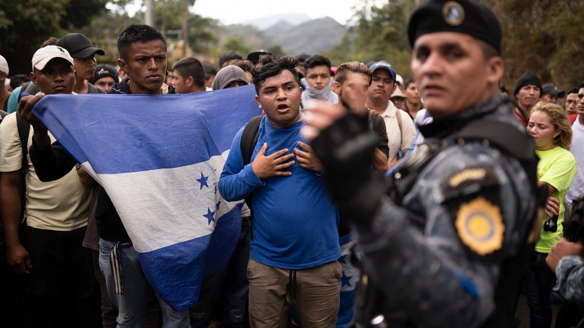 Honduran migrants walking in a group stop before Guatemalan police near Agua Caliente, Guatemala on Thursday on the border with Honduras. Hundreds of Honduran migrants started walking and hitching rides Wednesday from the city of San Pedro Sula, in a bid to form the kind of migrant caravan that reached the U.S. border in 2018. (AP Photo/Santiago Billy)
