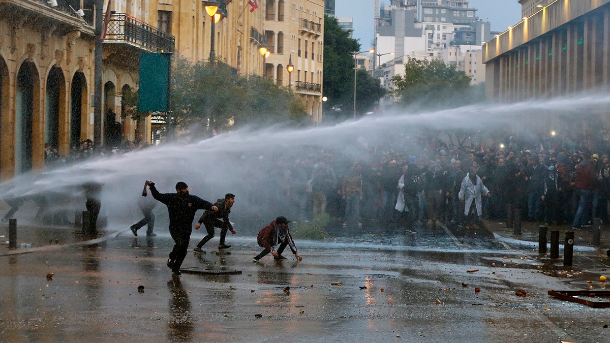 Anti-government demonstrators clash with riot police at a road leading to the parliament building in Beirut, Lebanon, Saturday, Jan. 18, 2020. Riot police fired tears gas and sprayed protesters with water cannons near parliament building to disperse thousands of people after riots broke out during a march against the ruling elite amid a severe economic crisis. (AP Photo/Bilal Hussein)