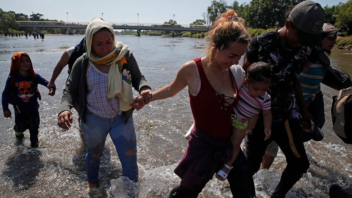 Central American migrants cross the Suchiate River by foot from Tecun Uman, Guatemala, to Mexico, on Monday. More than a thousand Central American migrants hoping to reach the United States marooned in Guatemala are walking en masse across a river leading to Mexico in an attempt to convince authorities there to allow them passage through the country. (AP Photo/Moises Castillo)