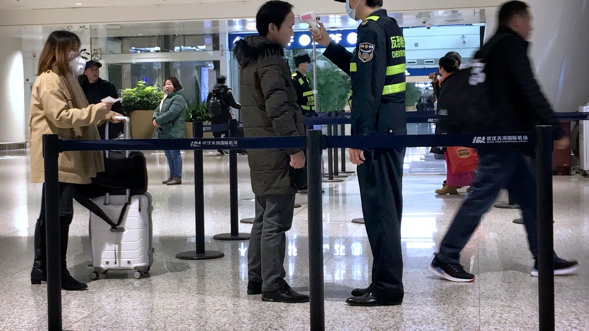 An official uses an infrared thermometer on a traveler at a health screening checkpoint at Wuhan Tianhe International Airport in Wuhan on Tuesday.