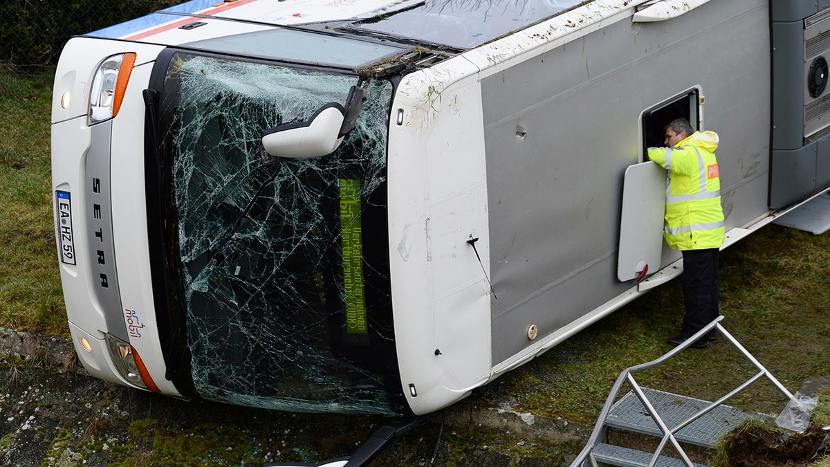 A police officer looks into a school bus that has crashed in Berka Vor Dem Hainich, near Eisenach, Germany, Thursday, Jan. 23, 2020. (Swen Pfoertner/dpa via AP)