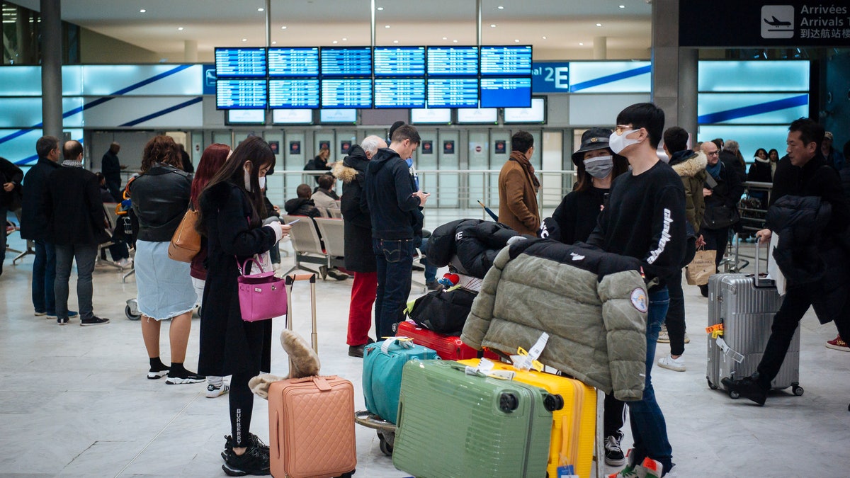 Travelers from Beijing, wearing masks, arrive at Charles de Gaulle airport, north of Paris, early Monday, Jan. 27, 2020. (AP Photo/Kamil Zihnioglu)