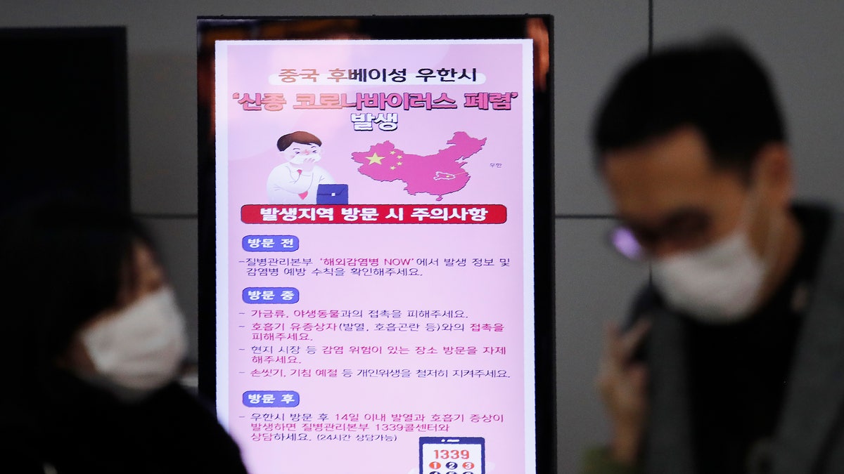 A poster warning about coronavirus is seen as passengers wear masks in a departure lobby at Incheon International Airport in Incheon, South Korea, Monday, Jan. 27, 2020. China on Monday expanded sweeping efforts to contain a viral disease by extending the Lunar New Year holiday to keep the public at home and avoid spreading infection. The sign reads " A new coronavirus occurs in Wuhan City, China." (AP Photo/Ahn Young-joon)