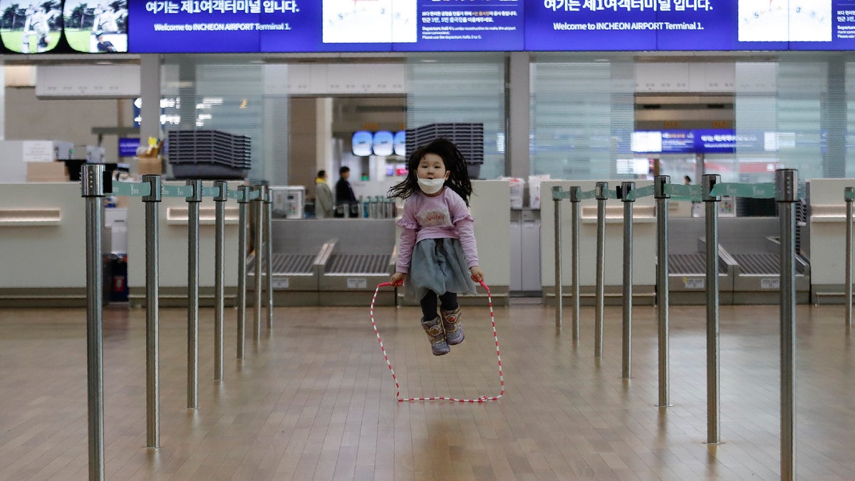 A girl wearing a mask skips rope at Incheon International Airport in Incheon, South Korea, Monday, Jan. 27, 2020. (AP Photo/Ahn Young-joon)