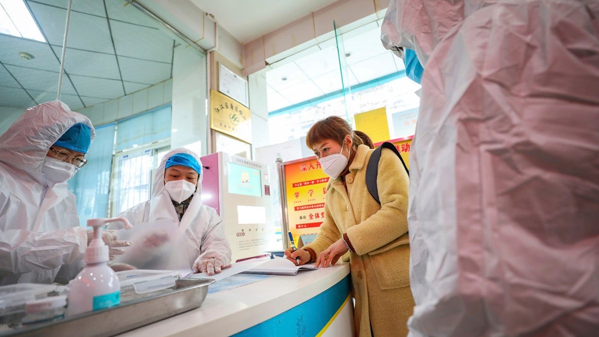 Medical workers in protective gear talk with a woman suspected of being ill with a coronavirus at a community health station in Wuhan in central China's Hubei Province on Monday.  (Chinatopix via AP)