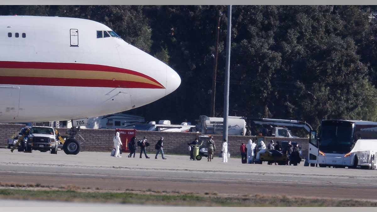 Passengers board buses after arriving on an airplane carrying U.S. citizens being evacuated from Wuhan, China, at March Air Reserve Base in Riverside, Calif. Jan. 29, 2020. The passengers will undergo additional screenings in California and be placed in temporary housing. Officials have not said how long they will stay there. (AP Photo/Ringo H.W. Chiu)