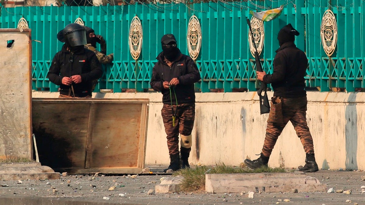 Security forces carry slingshots and a pellet air rifle during clashes with anti-government protesters in downtown Baghdad, Iraq on Thursday, Jan. The Iraqi military said it will resume operations with U.S.-led coalition forces after a three-week pause. (AP Photo/Hadi Mizban)