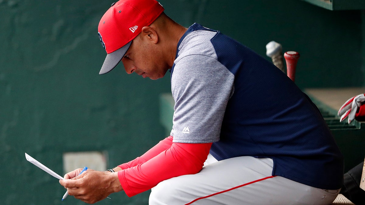FILE - In this March 20, 2019, file photo, Boston Red Sox manager Alex Cora looks over the lineup before the team's spring training baseball game against the Baltimore Orioles in Sarasota, Fla. Cora was fired by the Red Sox on Tuesday, Jan. 14, 2020, a day after baseball Commissioner Rob Manfred implicated him in the sport's sign-stealing scandal. (AP Photo/John Bazemore)