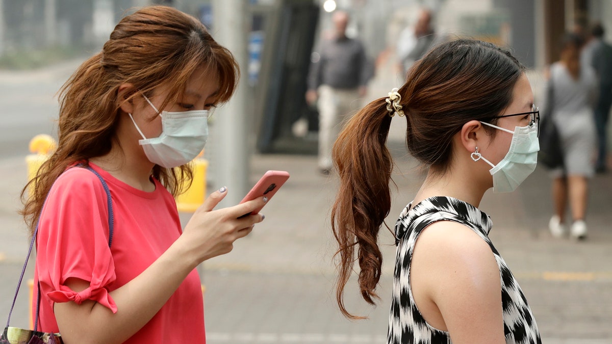 In this Jan. 2, 2020, file photo, pedestrians wear masks as smoke shrouds the Australian capital of Canberra, Australia.