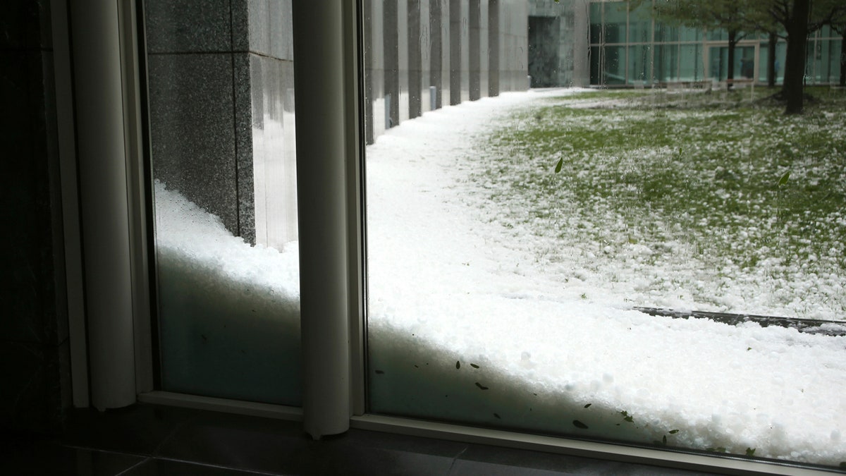 Golfball-sized hail carpet the lawn and drift against the building of Parliament House in Canberra, Australia, after a storm battered the Australian capital, Monday, Jan. 20, 2020.