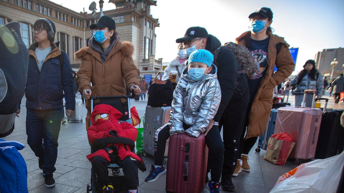 Travelers wear face masks as they walk outside of the Beijing Railway Station in Beijing.