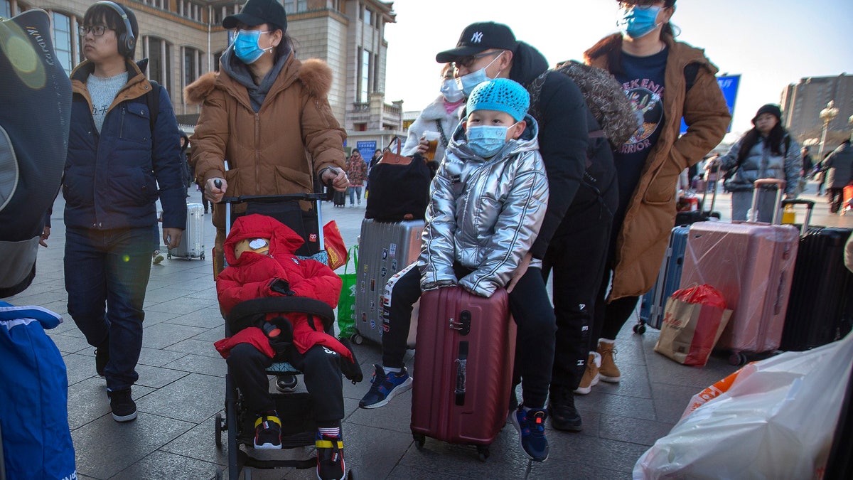 Travelers wear face masks as they walk outside of the Beijing Railway Station in Beijing.