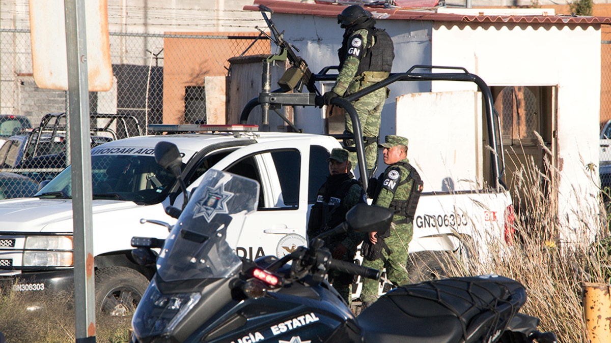 Members of the Mexican National Guard stand atop a vehicle as they keep watch outside the Cieneguillas state prison after sixteen inmates were killed and five were wounded in a brawl.