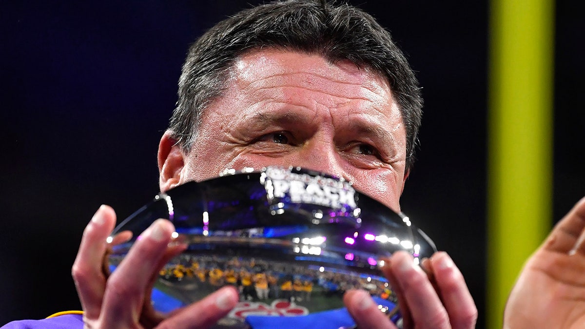 LSU coach Ed Orgeron holds the trophy after the team's Peach Bowl NCAA semifinal college football playoff game against Oklahoma, Saturday, Dec. 28, 2019, in Atlanta. LSU won 63-28. (AP Photo/John Amis)