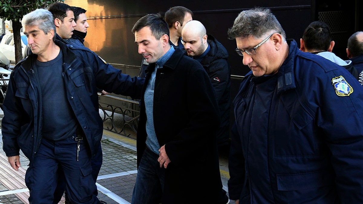 Greek police officers escorted two of the seven suspects allegedly involved in the fatal beating of Henderson as they disembarked a police bus at a court house in Patras city on Wednesday. (AP Photo/Giannis Androutsopoulos)