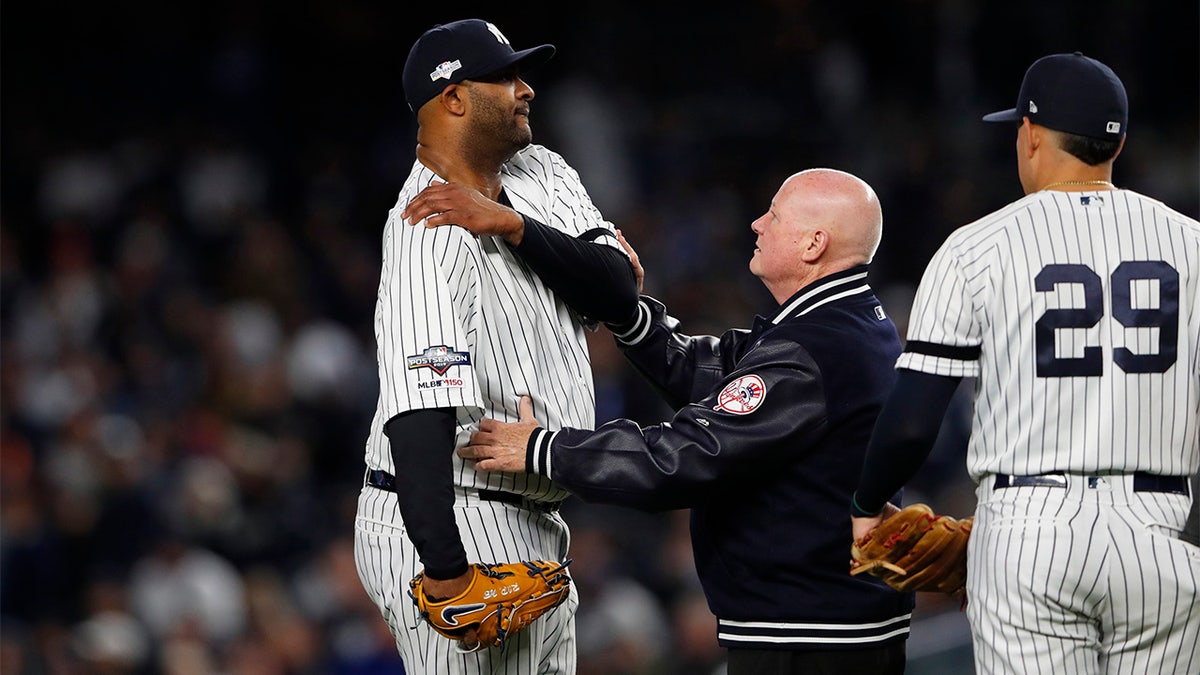 Oct 17, 2019; Bronx, NY, USA; New York Yankees pitcher CC Sabathia (52) reacts as he examined by trainer Steve Donohue after suffering an apparent injury against the Houston Astros as third baseman Gio Urshela (29) looks on during the eighth inning of game four of the 2019 ALCS playoff baseball series at Yankee Stadium.