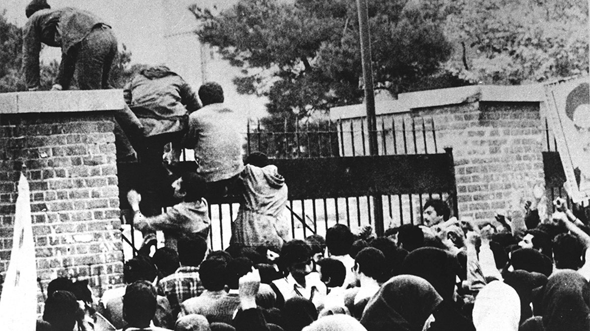 Iranian students climb over the wall of the US embassy in Tehran 04 November 1979.